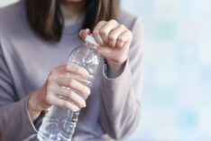 A woman opens the cap of a water bottle to drink. Health care concept.